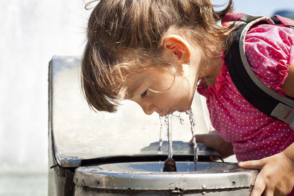 School girl drinking out of water fountain