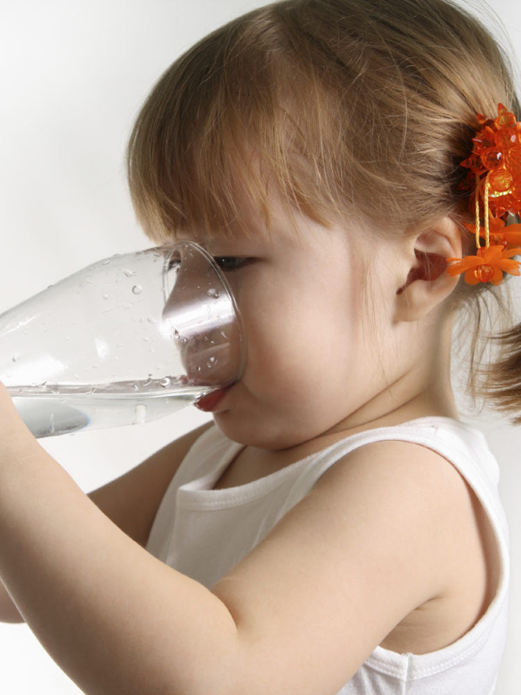 Little girl drinking water from a water filtration system