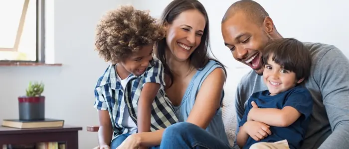 a family laughing while sitting on a couch