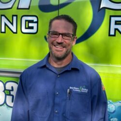 Barker and Sons technician posing in front of one of their service trucks - ready to help his customers have peace of mind.