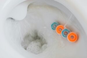 Flush the toilet with blue and orange cleaning tablets attached to the rim. This straightforward home plumbing tip helps keep your toilet fresh and challenges common myths about in-tank cleaners.